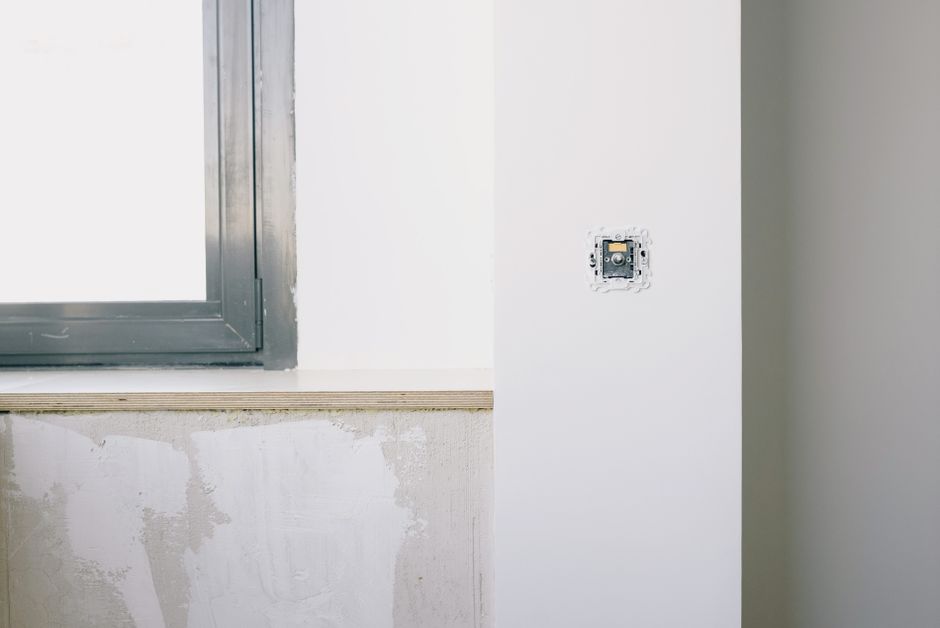 A repaired white wall beside a window in a bright room